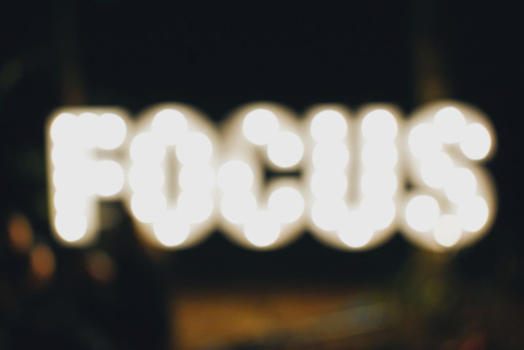 Photo flou d'un panneau lumineux en néon représentant le mot "FOCUS"